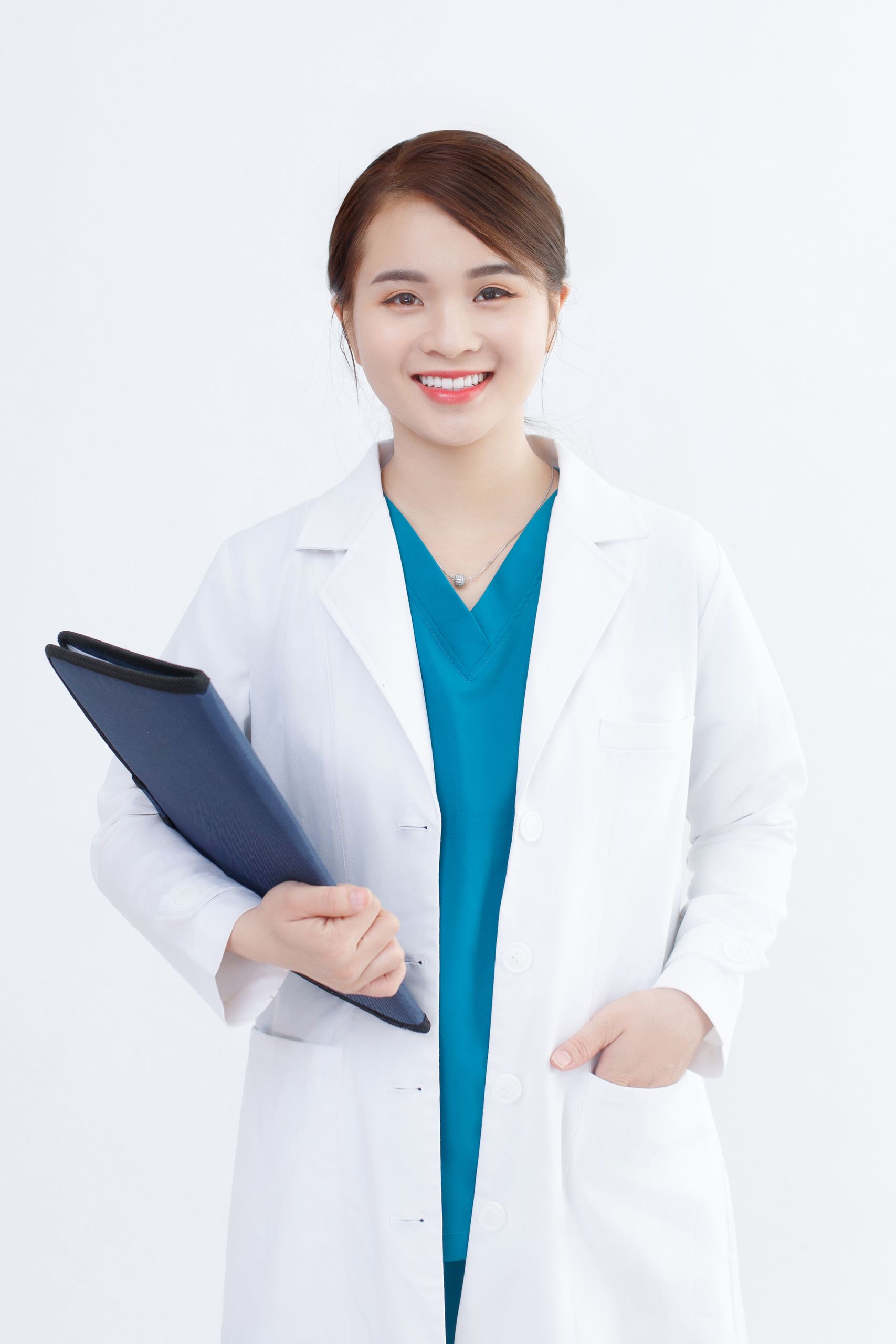 Smiling young female doctor in white coat holding a medical file indoors.